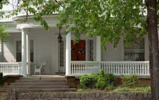 Victorian-style front porch with turned wood columns, balusters, and decorative railing details.