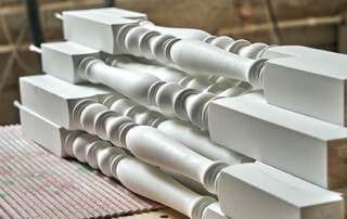 White paint-grade wood stair balusters for an interior railing.