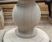 A single custom-turned red oak table base measuring 27 inches in diameter, shown on a workshop floor.