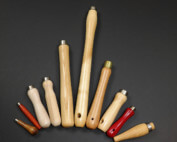 Assorted wood tool handles displayed with custom secondary operations including tenons, holes, tapers, and grooves.