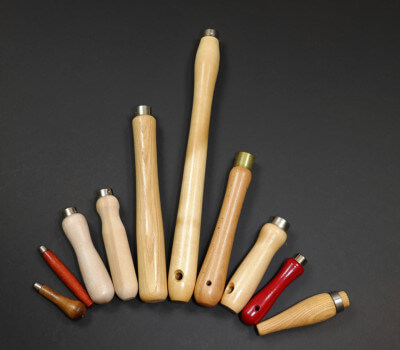 Assorted wood tool handles displayed with custom secondary operations including tenons, holes, tapers, and grooves.