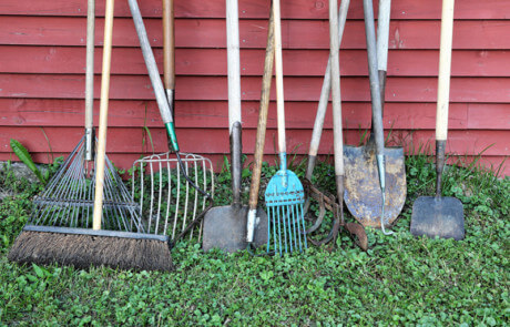 Wooden agricultural tool handles displayed in a row, designed for various farming and industrial applications.