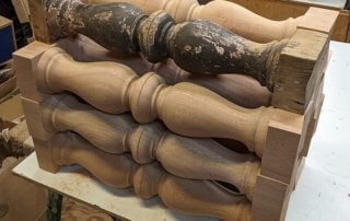 Multiple custom balusters made from paint-grade mahogany, each with a V-cut bottom.