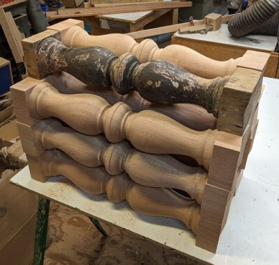 Multiple custom balusters made from paint-grade mahogany, each with a V-cut bottom.