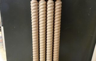 Close-up of twisted wood balusters arranged side by side on a work surface.