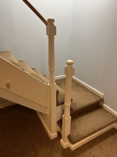 Custom Newel Posts Installed on Basement Stairs Two custom turned white painted newel posts installed at the base of a finished basement staircase in a Connecticut home